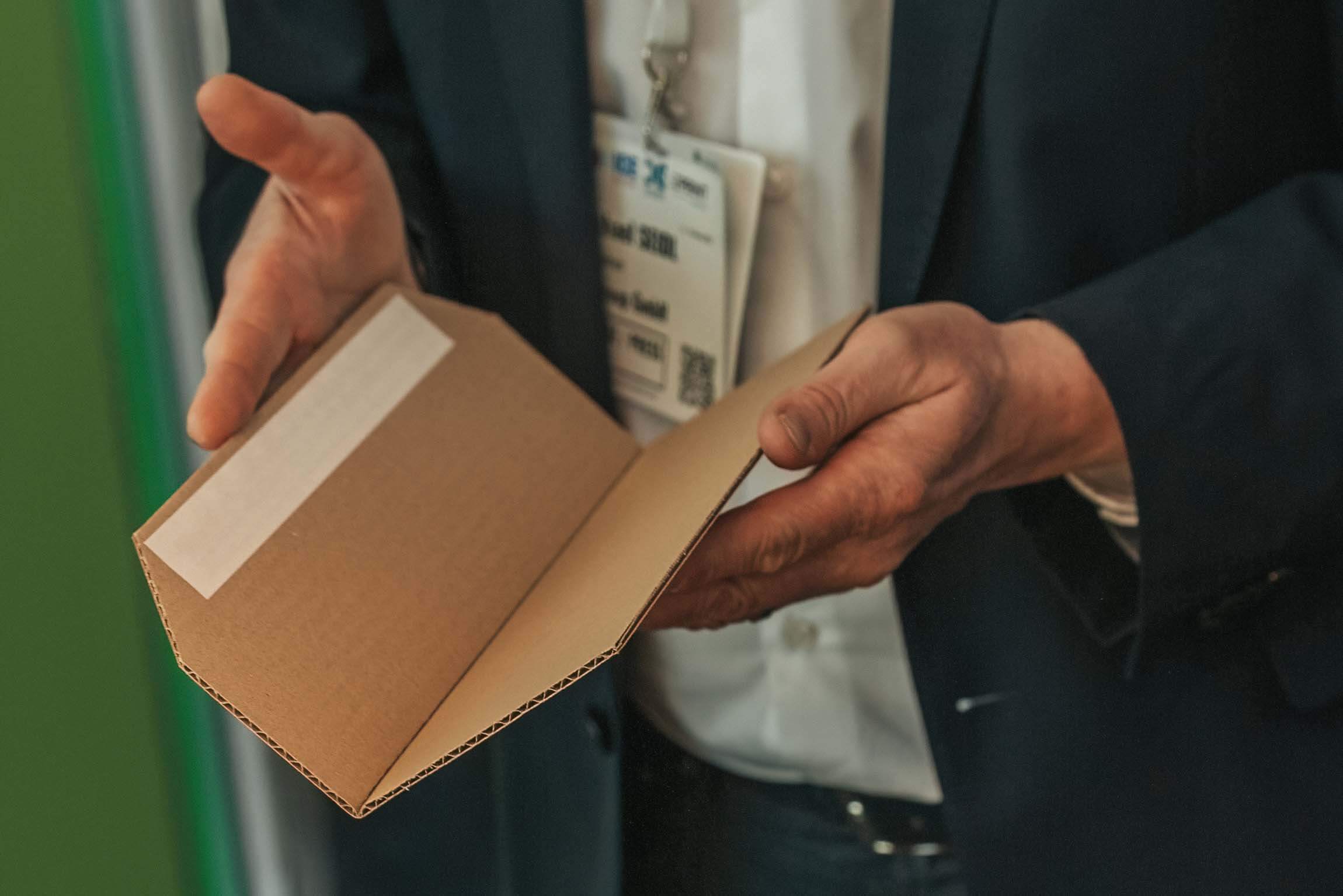Person inspecting a corrugated board folded precisely using liquid creasing 