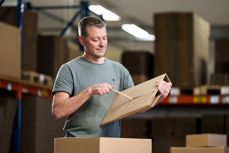 Person opening a shipping package using the tear strip 