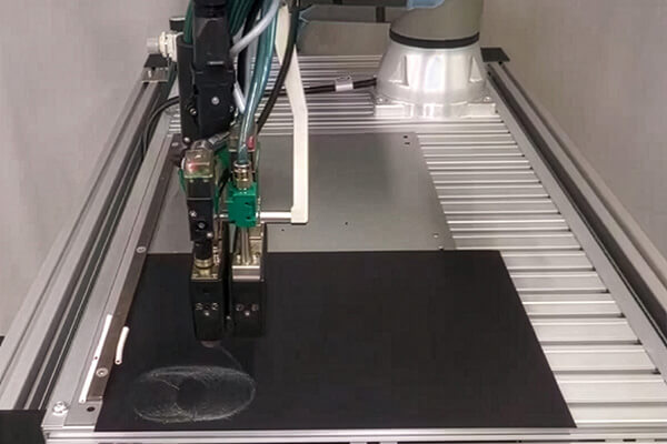 Aplicación por spray asistida por robots sobre un sustrato negro con cabezal de spray Aero.