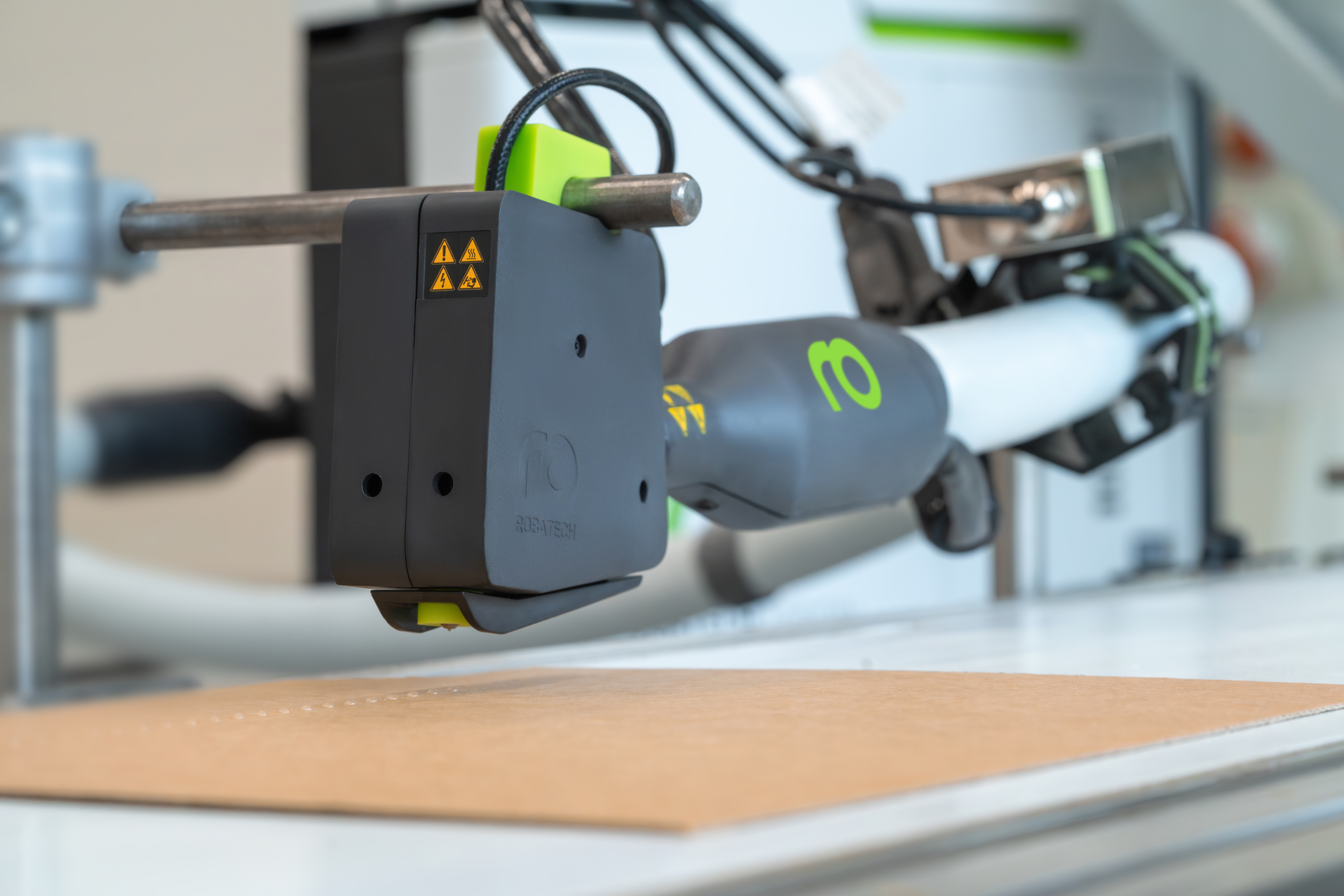 Tête d'application Volta avec tuyau chauffant Performa et unité de commande, fondoir de colle Vision à l'arrière-plan